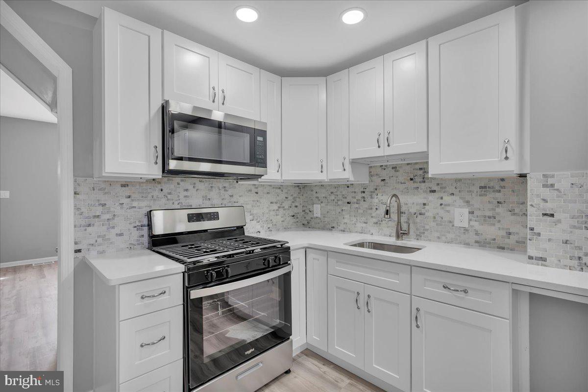 407 Powell Street Gloucester City, NJ 08030 - Photo 7 of 22 a kitchen with granite countertop white cabinets sink and stainless steel appliances