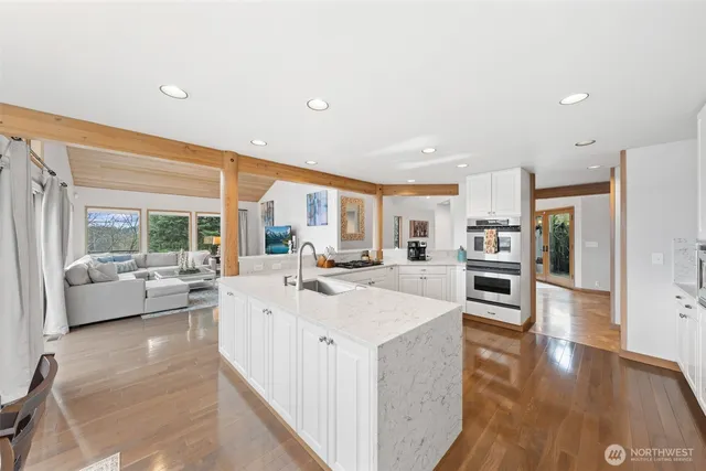 a large white kitchen with a large window and stainless steel appliances