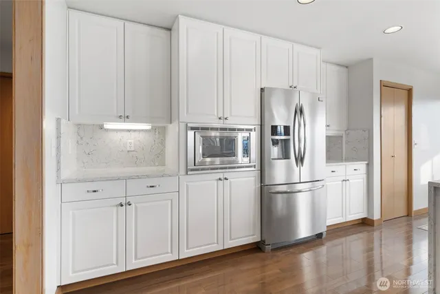 a kitchen with stainless steel appliances granite countertop a refrigerator and white cabinets