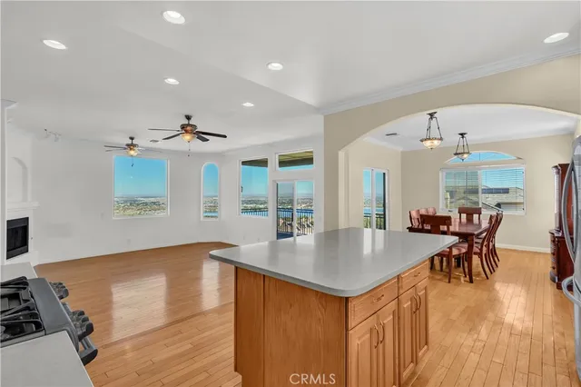 an open kitchen with granite countertop a stove and white cabinets with wooden floor
