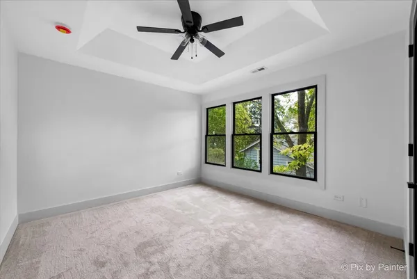 an empty room with windows and ceiling fan