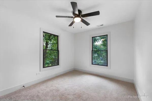 an empty room with windows and fan