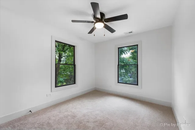 an empty room with windows and fan