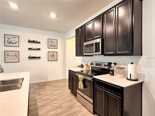 a view of kitchen with microwave stove refrigerator dining table and chairs