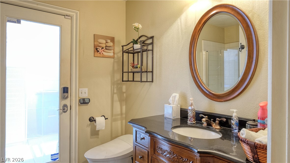3704 North Campbell Road Las Vegas, NV 89129 - Photo 23 of 38 A well-appointed bathroom features a dark vanity with a sleek countertop and an oval framed mirror.