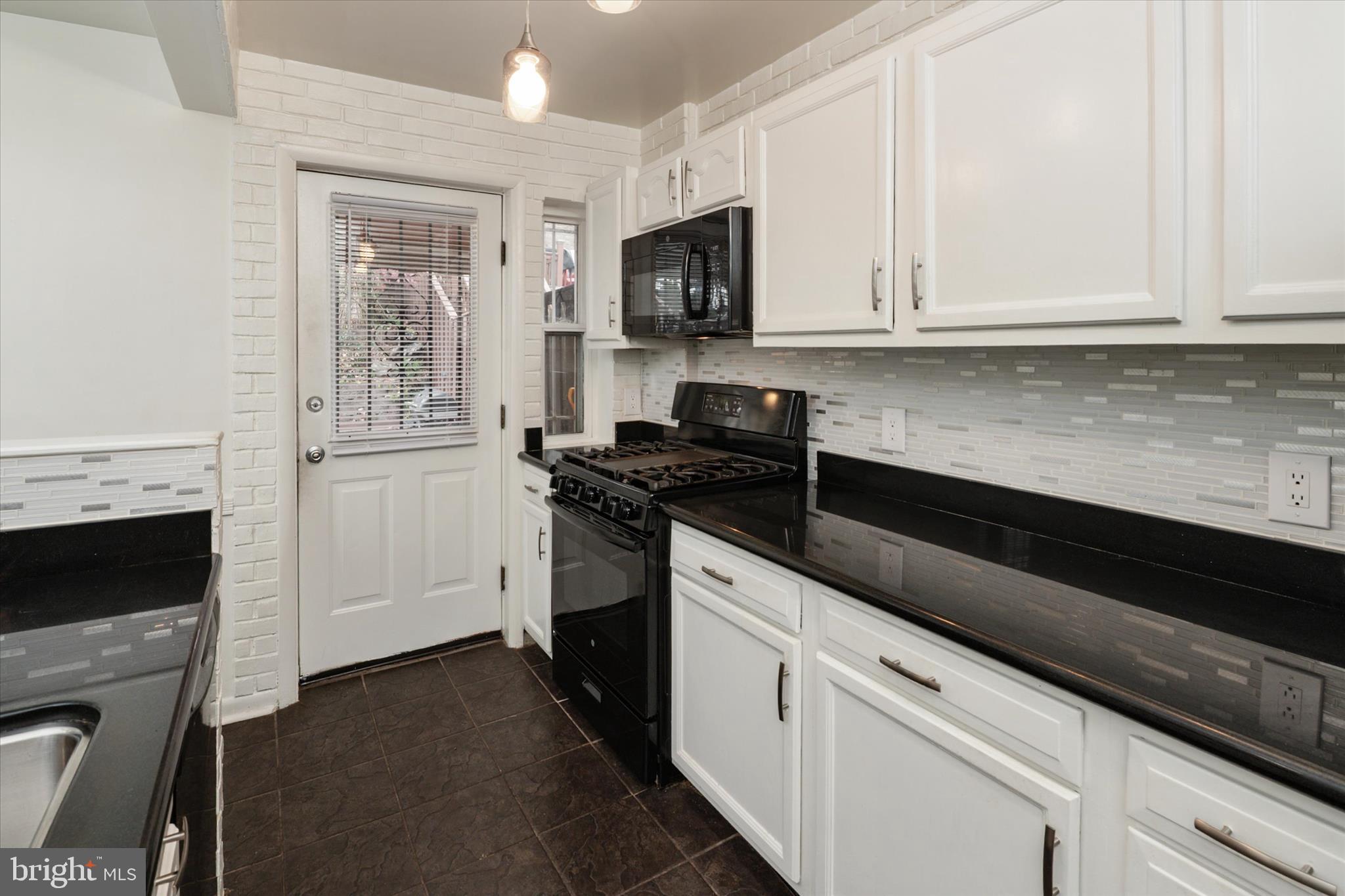 1353 Morris Road Southeast Washington, DC 20020 - Photo 11 of 32 a kitchen with granite countertop white cabinets and black appliances