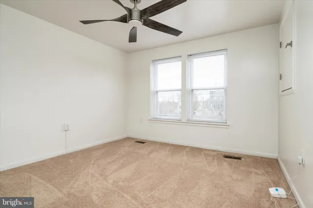 an empty room with a window and a fan