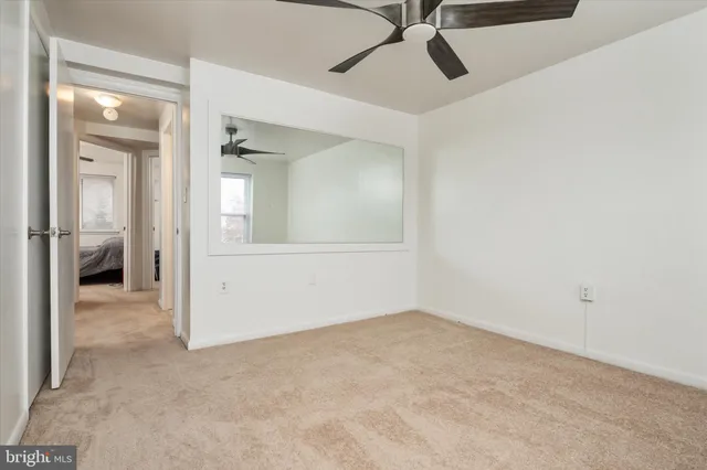 an empty room with a mirror and a ceiling fan