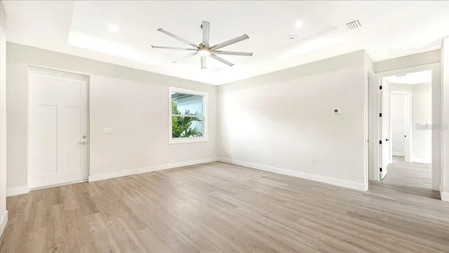 an empty room with wooden floor fan and windows