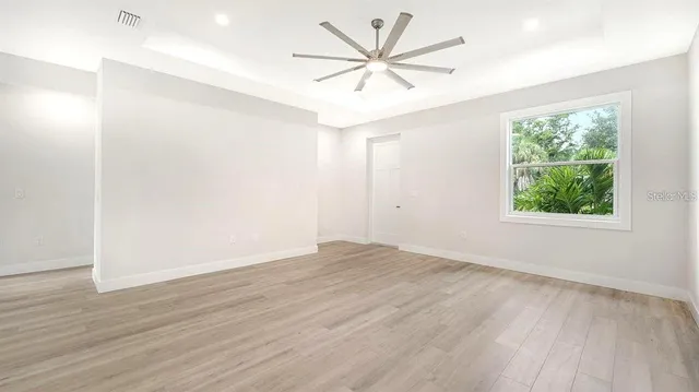 an empty room with wooden floor and windows