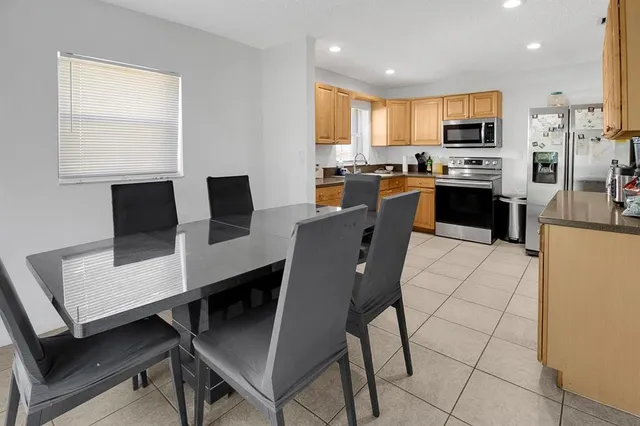a kitchen with stainless steel appliances a stove a refrigerator a sink a dining table and chairs