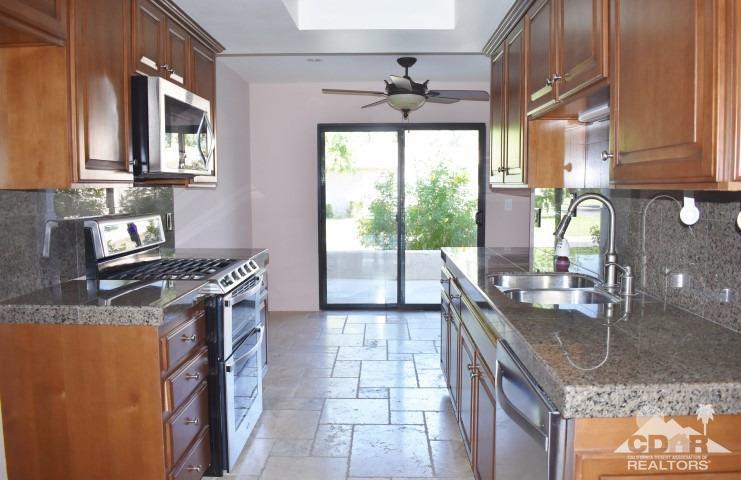 6243 East Driver Road Palm Springs, CA 92264 - Photo 6 of 14 a kitchen with stainless steel appliances granite countertop a sink a stove and a wooden cabinets
