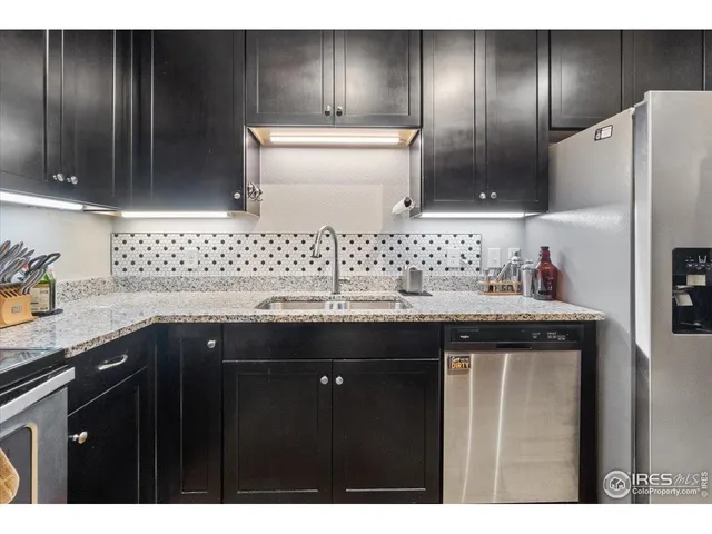 a kitchen with stainless steel appliances granite countertop a refrigerator a stove and a sink