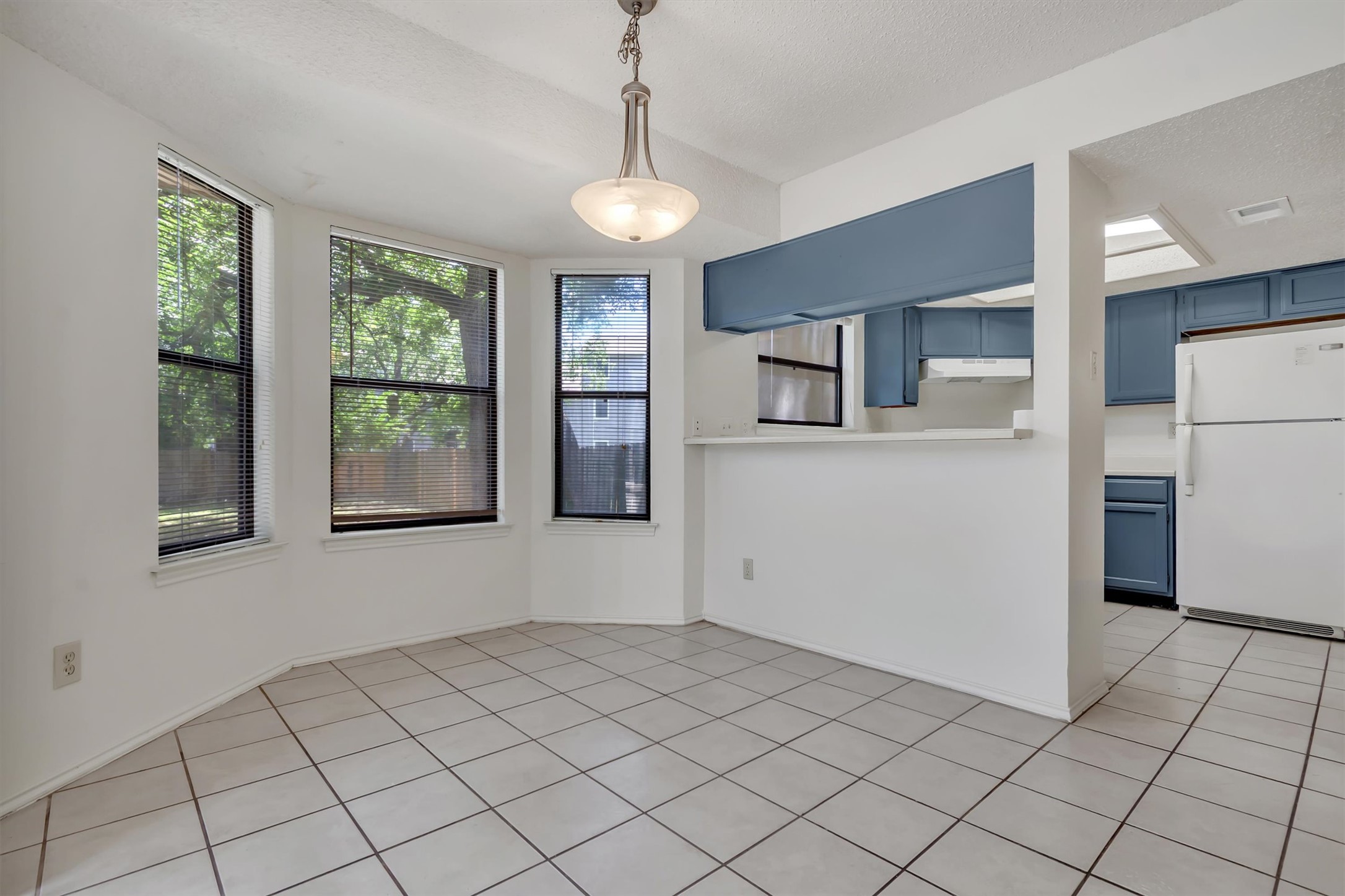 7802 Topawa Cove, Unit B Austin, TX 78729 - Photo 13 of 32 A well-lit dining area with a breakfast bar, tiled floors and views of mature trees from multiple windows.