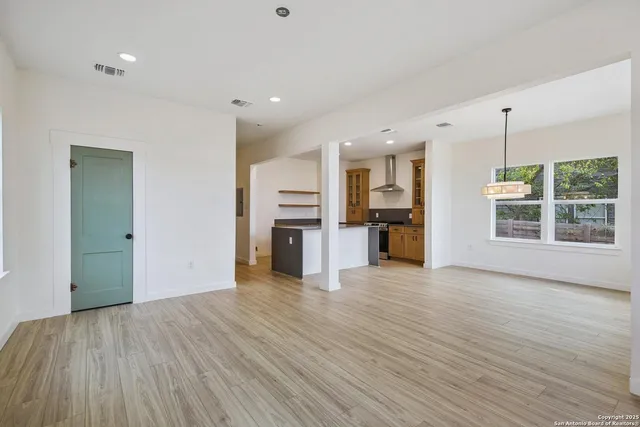 a view of a big room with wooden floor and a kitchen