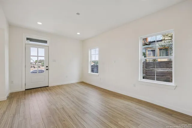 a view of an empty room with wooden floor and a window
