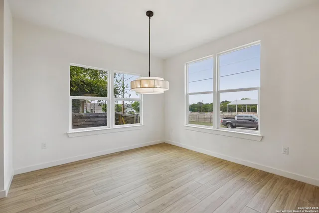 a view of an empty room with a window and wooden floor