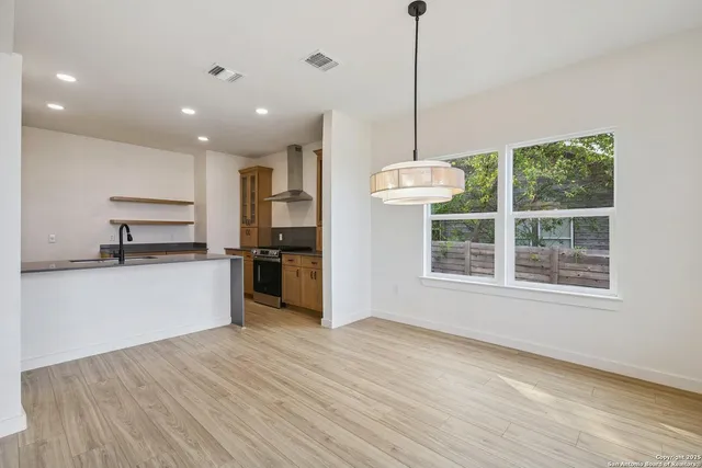 a view of kitchen with stainless steel appliances granite countertop a stove top oven a sink with wooden floor and cabinets
