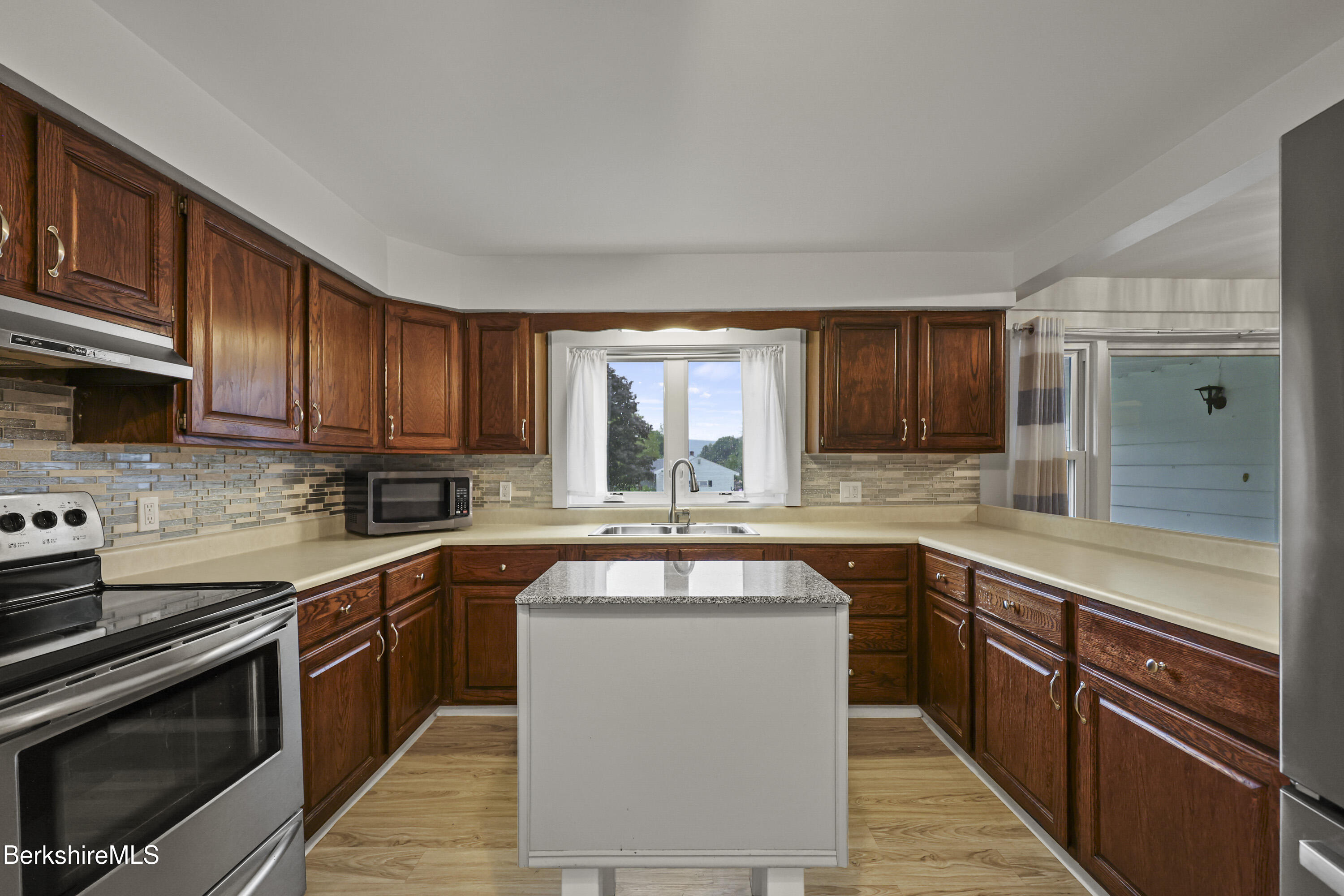 41 Deming Street Dalton, MA 01226 - Photo 16 of 35 a kitchen with stainless steel appliances granite countertop wooden cabinets a sink and dishwasher a stove top oven with wooden floor