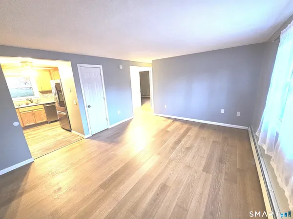 a view of an empty room with wooden floor and a window