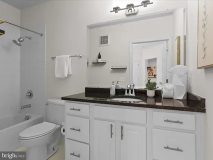 a bathroom with a granite countertop toilet a sink and a mirror