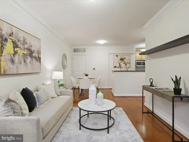 a living room with furniture and a dining table with wooden floor