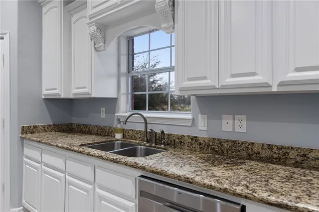 a kitchen with granite countertop white cabinets and a sink