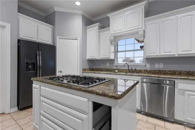 a kitchen with granite countertop stainless steel appliances a stove refrigerator sink and cabinets