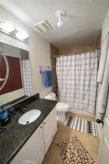a bathroom with a granite countertop sink toilet a mirror a vanity and shower