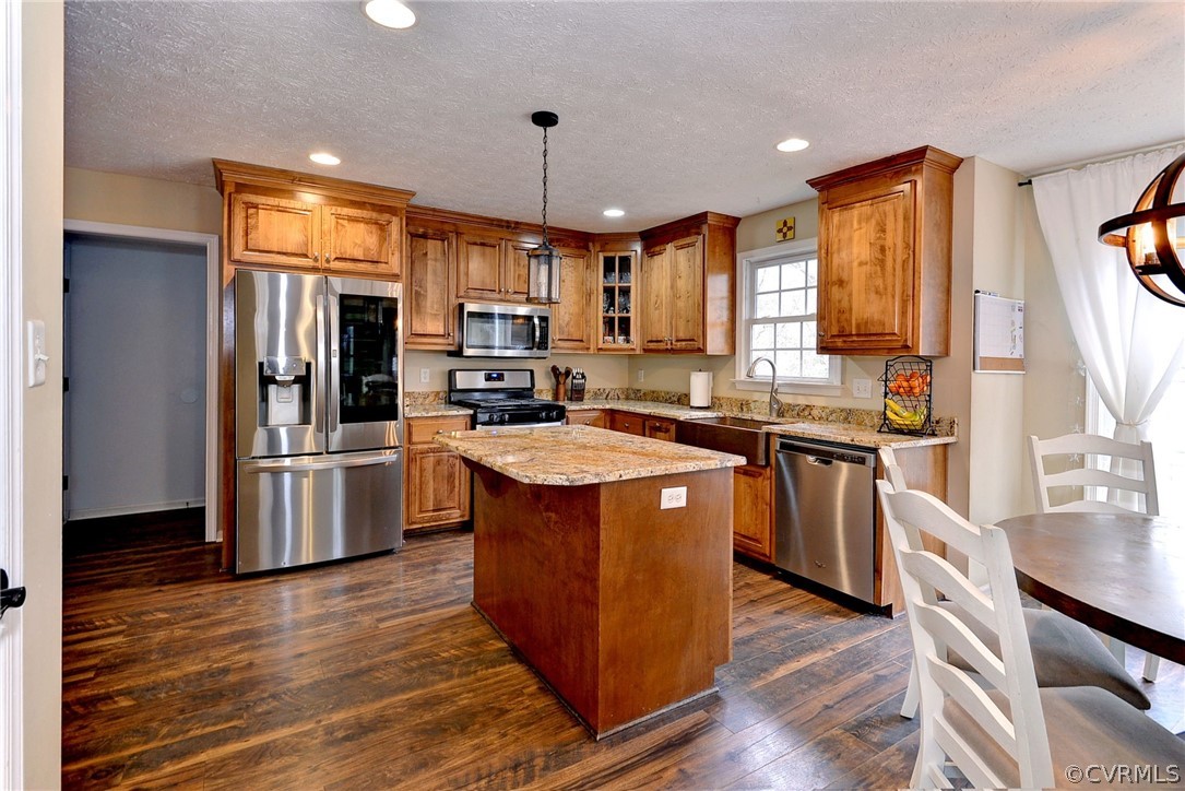 8416 Down Patrick Way Williamsburg, VA 23188 - Photo 13 of 47 a kitchen with stainless steel appliances granite countertop a stove top oven a refrigerator and a island with wooden floor