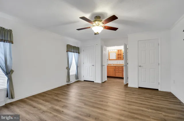 a view of empty room with wooden floor and fan