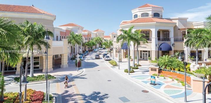 215 Southwest 10th Street Hallandale Beach, FL 33009 - Photo 17 of 18 a view of a white house with a fountain and a table and chairs under an umbrella