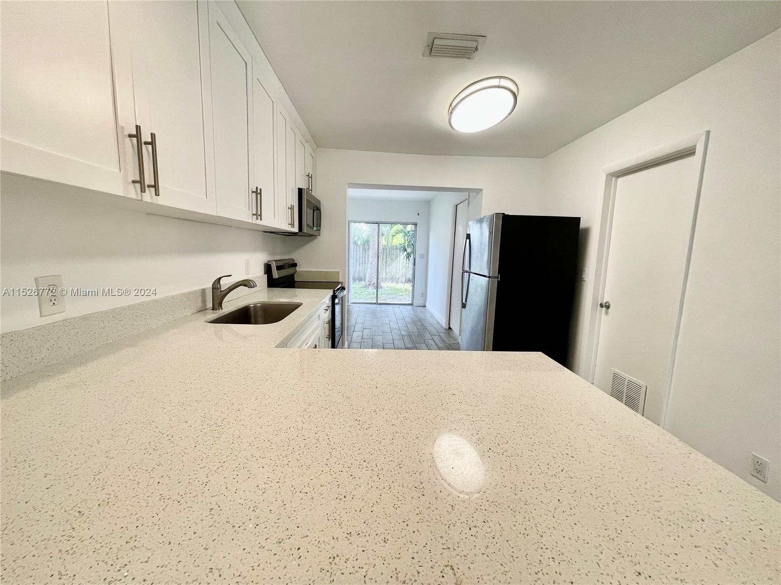 215 Southwest 10th Street Hallandale Beach, FL 33009 - Photo 3 of 18 a kitchen with stainless steel appliances a refrigerator a sink a stove and cabinets