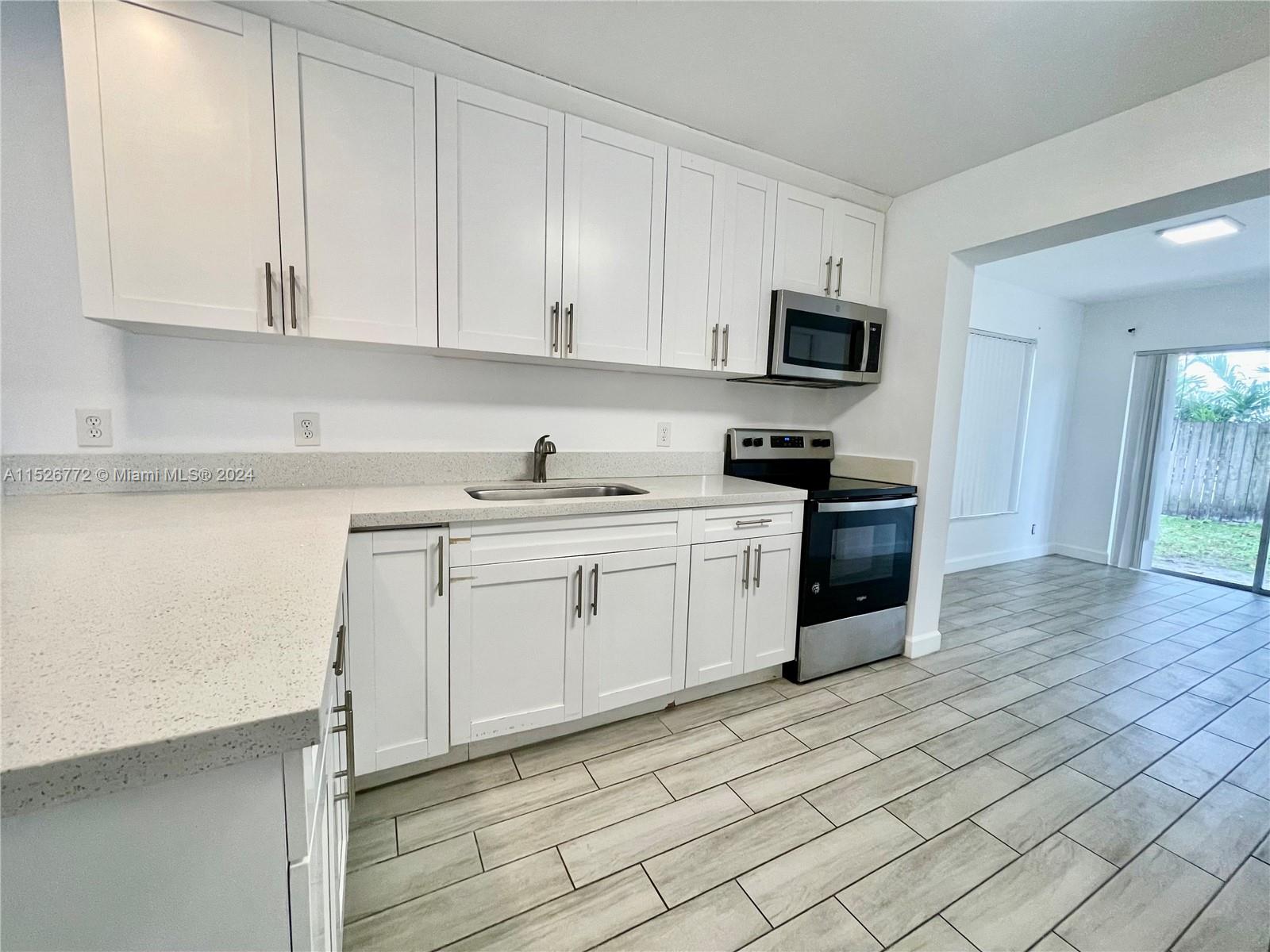 215 Southwest 10th Street Hallandale Beach, FL 33009 - Photo 4 of 18 a kitchen with stainless steel appliances granite countertop a sink and dishwasher a stove top oven with wooden floor