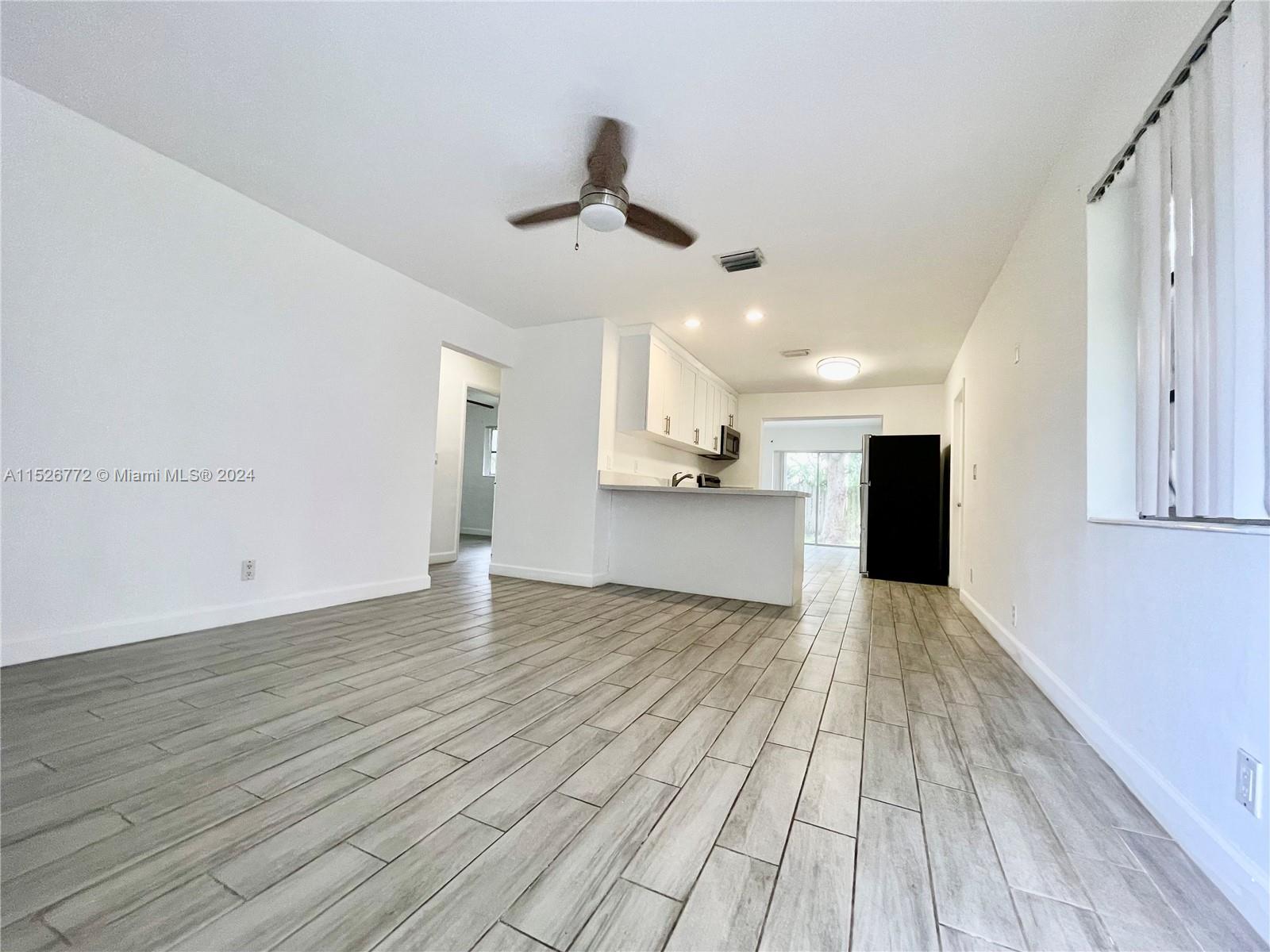 215 Southwest 10th Street Hallandale Beach, FL 33009 - Photo 5 of 18 a view of empty room with wooden floor and window