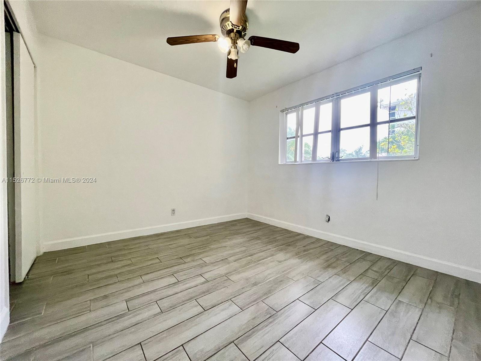 215 Southwest 10th Street Hallandale Beach, FL 33009 - Photo 8 of 18 a view of an empty room with window and wooden floor