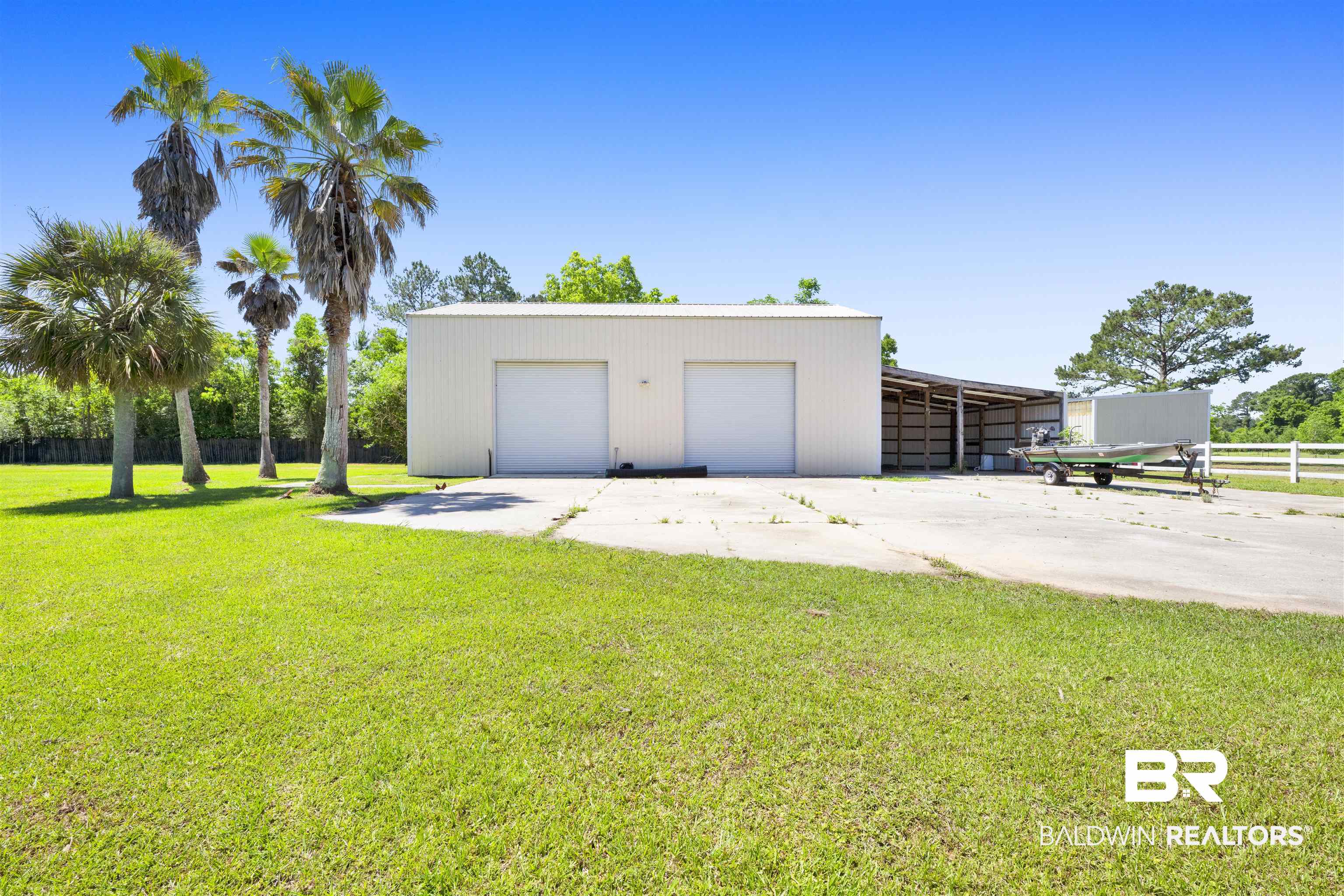 12944 Anna's Way Stapleton, AL 36578 - Photo 19 of 64 Metal outbuilding featuring two garage doors, an open-sided covered structure, and a concrete pad
