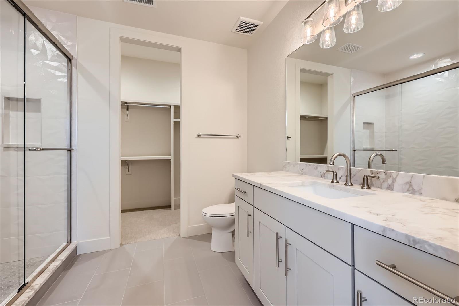 5841 Powell Road Parker, CO 80134 - Photo 28 of 50 a spacious bathroom with a granite countertop sink a toilet and a mirror