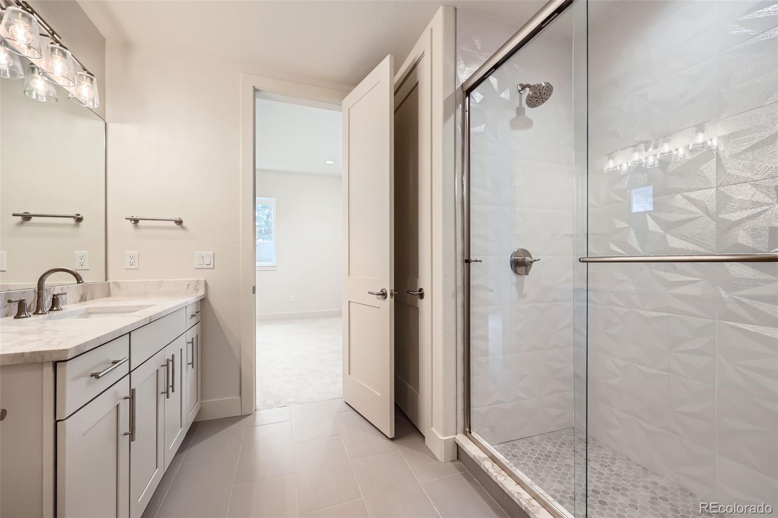 5841 Powell Road Parker, CO 80134 - Photo 29 of 50 a bathroom with a double vanity sink a mirror and shower