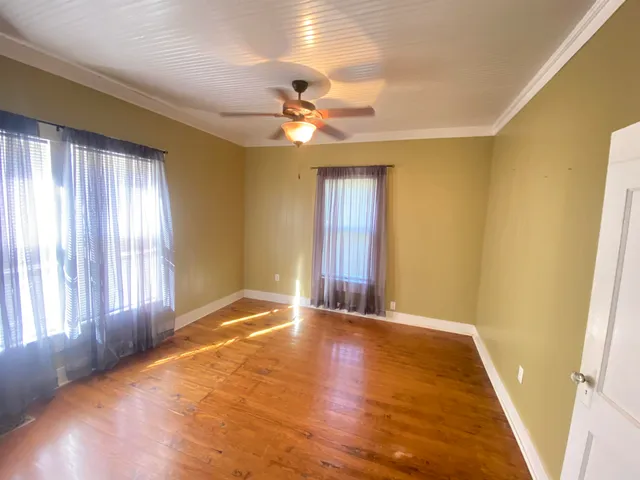 a view of an empty room with window and chandelier fan