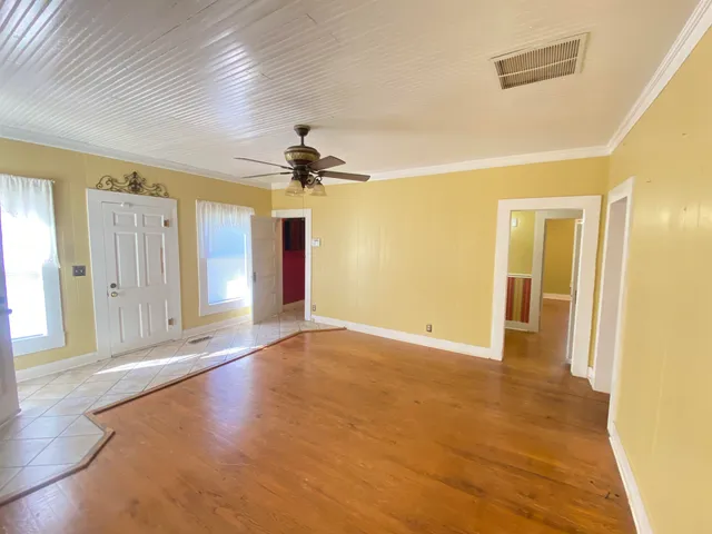 a view of an empty room with window and wooden floor