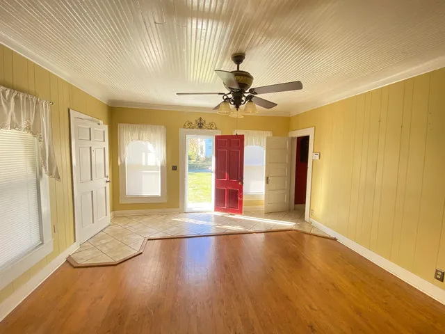 a view of an empty room with window and wooden floor