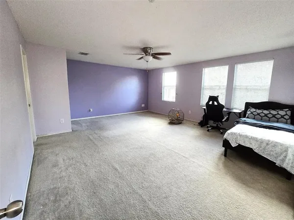 a spacious bedroom with a bed couch and window