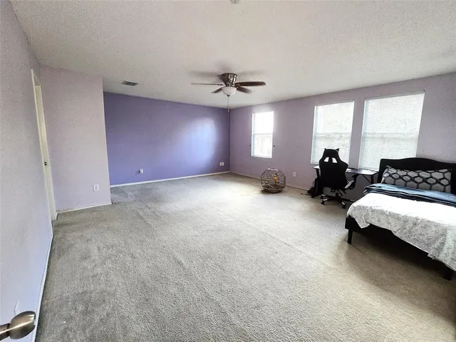 a spacious bedroom with a bed couch and window