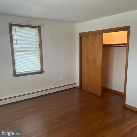 an empty room with wooden floor closet and windows