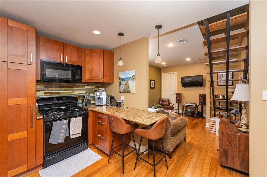 2220 Sarah Street, Unit 2 Pittsburgh, PA 15203 - Photo 5 of 34 a kitchen with stainless steel appliances kitchen island granite countertop a stove a sink a refrigerator white cabinets and wooden floor