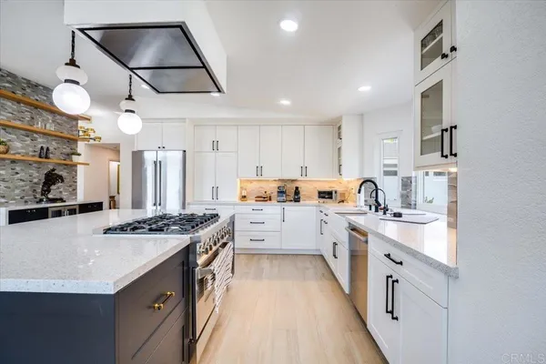 a large white kitchen with kitchen island a stove a sink a refrigerator and cabinets