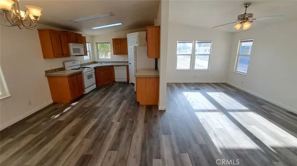 a kitchen with stainless steel appliances granite countertop a refrigerator a sink dishwasher a stove and white countertops with wooden floor