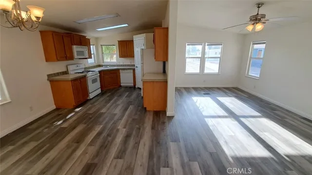 a kitchen with stainless steel appliances granite countertop a refrigerator a sink dishwasher a stove and white countertops with wooden floor