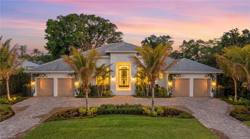 View of front of house featuring an attached garage, a yard, and stucco siding
